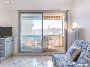 a living room with a couch and a sliding glass door at Appartement la Galerne Royan-Pontaillac - plage casino in Vaux-sur-Mer