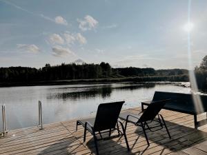 two chairs and a table on a dock next to a lake at HYGGE Sauna&Fishing House in Jagėlonys Kalniniai