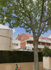 two children standing under a tree in front of a building at Piso acogedor con terraza in Ciudad Real