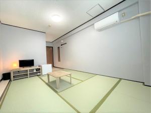 ein leeres Zimmer mit einem Tisch und einer weißen Wand in der Unterkunft Portside美崎町 離島ターミナル徒歩3分 室内リニューアルOPEN in Ishigaki-jima