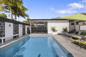 a swimming pool in front of a house at Ellie's Holiday Escape in Coffs Harbour