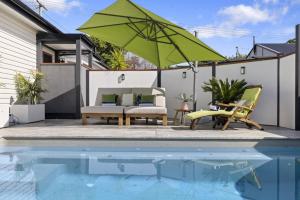 a patio with a pool and a green umbrella at Ellie's Holiday Escape in Coffs Harbour