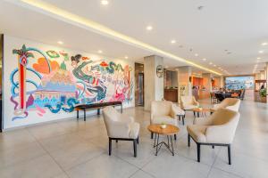 日惹的住宿－Arte Hotel Yogyakarta，大堂设有椅子和墙上的大画作