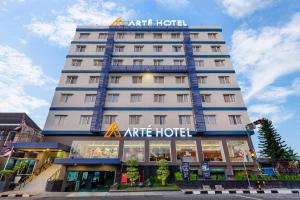 a tall white hotel with a sign on it at Arte Hotel Yogyakarta in Yogyakarta