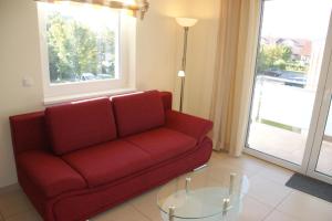 ein Wohnzimmer mit einem roten Sofa und einem Glastisch in der Unterkunft Blaue Perle Wohnung Nr 16-3 in Schönberger Strand
