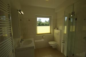 ein Bad mit einem Waschbecken, einem WC und einem Fenster in der Unterkunft Blaue Perle Wohnung Nr 16-3 in Schönberger Strand