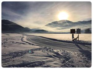a road in the snow with the sun in the sky at Gästehaus Wiesegg in Reit im Winkl