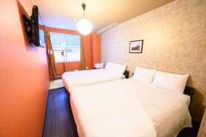 2 Betten in einem Zimmer mit orangefarbenen Wänden in der Unterkunft Hiroshima Wabisabi hostel 広島ワビサビ ホステル in Hiroshima