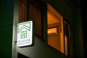 ein Schild an der Seite eines Gebäudes mit Fenster in der Unterkunft Hiroshima Wabisabi hostel 広島ワビサビ ホステル in Hiroshima