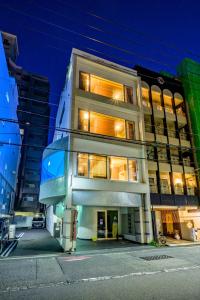 un edificio alto de color blanco con ventanas iluminadas por la noche en Hiroshima Wabisabi hostel 広島ワビサビ ホステル, en Hiroshima