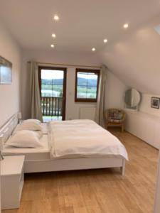 1 Schlafzimmer mit einem großen weißen Bett und 2 Fenstern in der Unterkunft Luxury 10-bed villa with view pool playground in Horní Planá