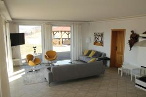 a living room with a gray couch and chairs and a window at Luxury 10-bed villa with view pool playground in Horní Planá