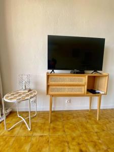 a television on a wooden stand with a table at Studio apartment Fréjus in Fréjus