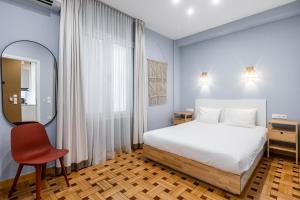1 dormitorio con cama, espejo y silla en Kolonaki Suites by Olala Homes, en Atenas