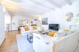 een woonkamer met witte meubels en een televisie bij Can Verd in Pollença