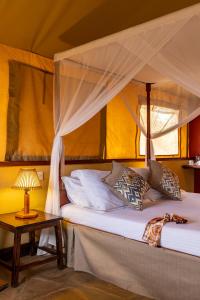 a bedroom with a bed with a canopy and a table at Sentrim Tsavo Lodge in Tsavo