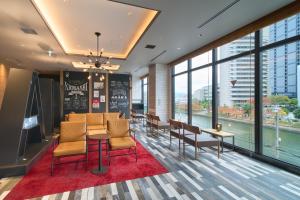 a waiting room with chairs and tables and windows at Via Inn Prime Osaka Kyobashi in Osaka