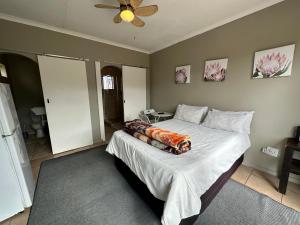 a bedroom with a large bed with a ceiling fan at Cornerstone Guest House in Polokwane