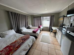 a hotel room with two beds and a kitchen at Cornerstone Guest House in Polokwane