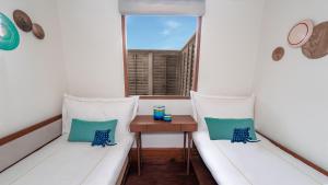 Un balcón con 2 sillas blancas y una mesa. en Anantara Kihavah Maldives Villas, en Atolón Baa