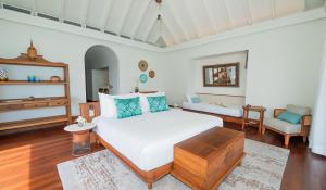 a bedroom with a bed and a living room at Anantara Kihavah Maldives Villas in Baa Atoll