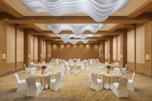 um salão de banquetes com mesas brancas e cadeiras brancas em Hyatt Place Vijayawada em Vijayawada