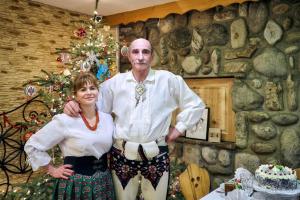 Un uomo e una donna in piedi di fronte a un albero di Natale di Willa Izydor, widok na Tatry, pyszne posiłki a Kościelisko