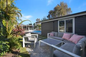 a patio with a couch and a table and chairs at Woy Woy Staycation - Heated Pool & Hot Tub & Games Room in Woy Woy