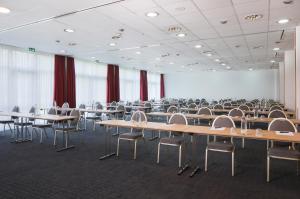 uma grande sala com mesas e cadeiras e cortinas vermelhas em H+ Hotel Hannover em Hanôver