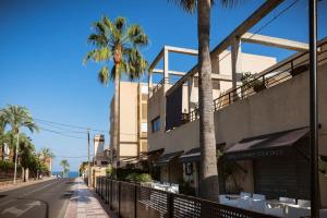 a building with chairs and palm trees on a street at Longbeach Smart Muchavista in Alicante