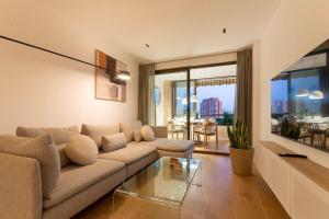 uma sala de estar com um sofá e uma mesa de vidro em Longbeach Smart Muchavista em Alicante
