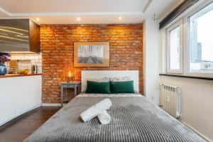 een bed in een kamer met een bakstenen muur bij Chmielna 106B Centrum by VAYA STAYS in Warschau