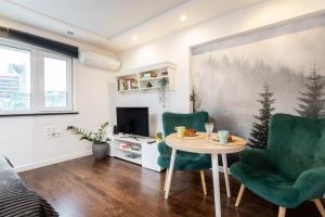 een woonkamer met een tafel en 2 groene stoelen bij Chmielna 106B Centrum by VAYA STAYS in Warschau