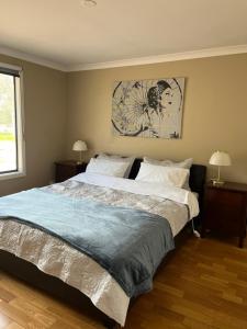 a bedroom with a large bed with two lamps and a painting at Thie My Chree Retreat in Herne Hill