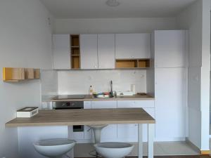 eine Küche mit weißen Schränken und einer hölzernen Arbeitsplatte in der Unterkunft Mila Apartment sajam in Novi Sad