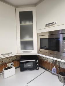 a kitchen with white cabinets and a microwave at La casa sobre el rÍo in Cuenca