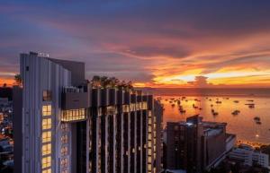 a sunset over a city with boats in the water at Edge Central PATTAYA Sky Residence with Infinity Pool & Free Netflix in Pattaya Central