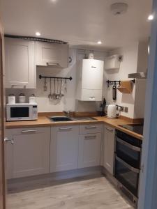 a kitchen with white cabinets and white appliances at 2 The Maltings Apartments in Shepton Mallet