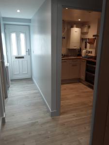 a kitchen with a white door and a wooden floor at 2 The Maltings Apartments in Shepton Mallet