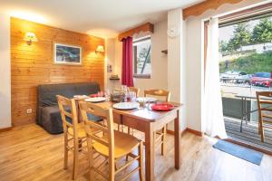 a dining room with a table and chairs and a couch at Le Silène - Appt pour 6 in Chamrousse