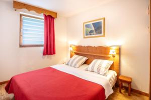 um quarto com uma cama vermelha e branca e uma janela em Le Silène - Appt pour 6 em Chamrousse