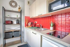a kitchen with a sink and a red tiled wall at Expédition Malouine - Appt à 30m de la plage in Saint Malo