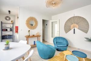 a living room with a white table and blue chairs at Expédition Malouine - Appt à 30m de la plage in Saint Malo
