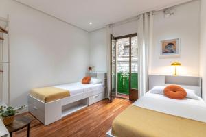 two beds with orange pillows in a bedroom at INAR céntrico apartamento junto Ayuntamiento & Ría in Bilbao