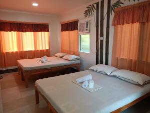 two beds in a room with orange curtains at Agta Beach Resort in Biliran