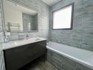 ein Bad mit einem Waschbecken, einer Badewanne und einem Fenster in der Unterkunft Le Clos Guiton in La Rochelle