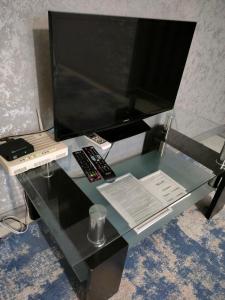 a glass table with a computer monitor and remote controls at Квартира на Панфилова "Арбат" 1 комн in Almaty