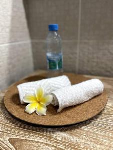 a towel and a flower on a coaster with a bottle of water at City Lodge Appartment in Te Auae