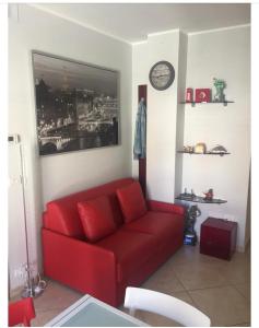 um sofá vermelho numa sala de estar com um relógio em delizioso appartamento em San Benedetto del Tronto