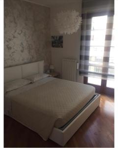 um quarto com uma cama branca e uma janela em delizioso appartamento em San Benedetto del Tronto